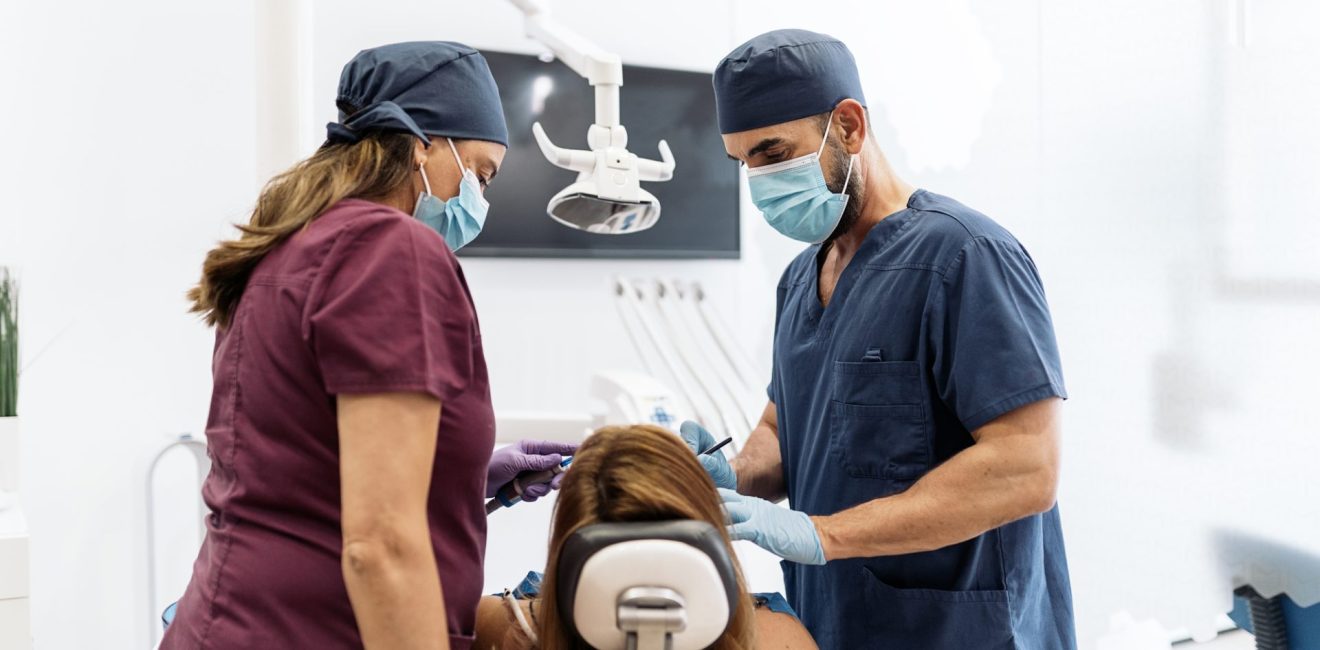 Stock photo of two dental clinic workers with patient during her revision.