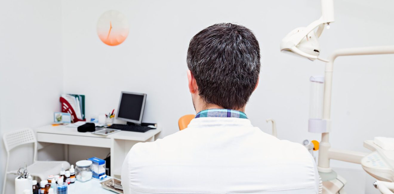 A dentist in a dental clinic. The work of the dentist. With his back to the camera. Admission to Dentistry.