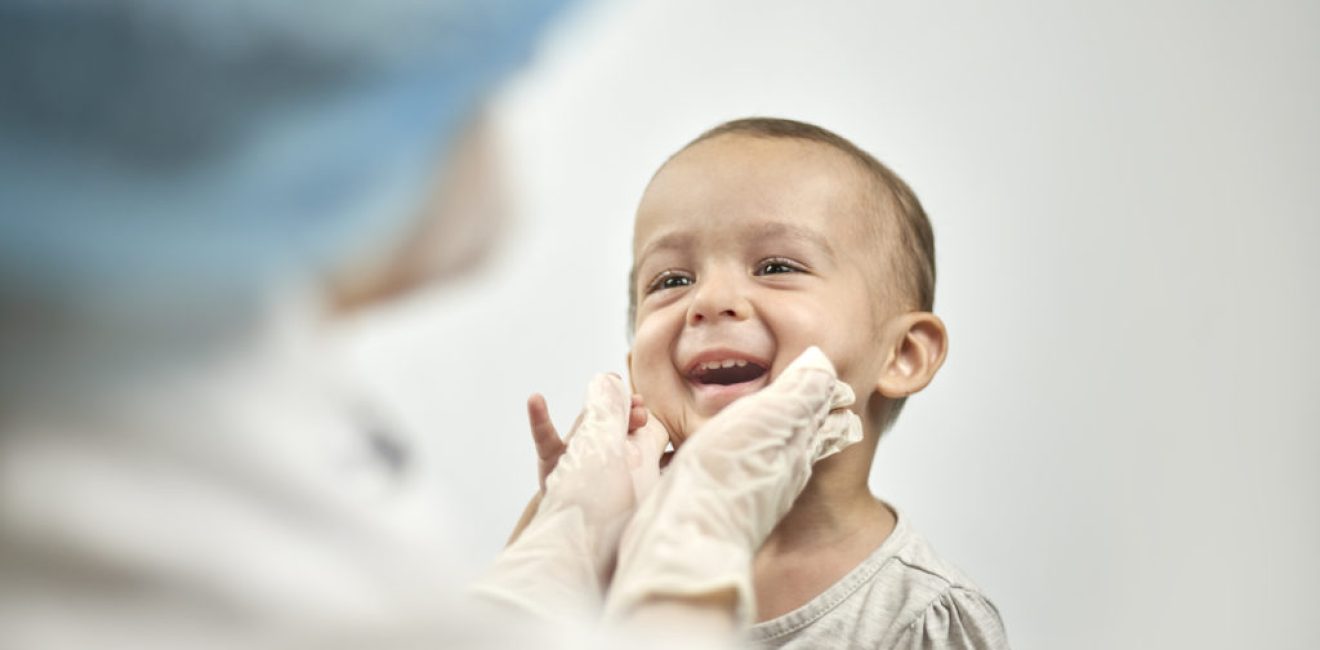 Pediatrician checking baby teeth. Dentist examines teeth of baby boy